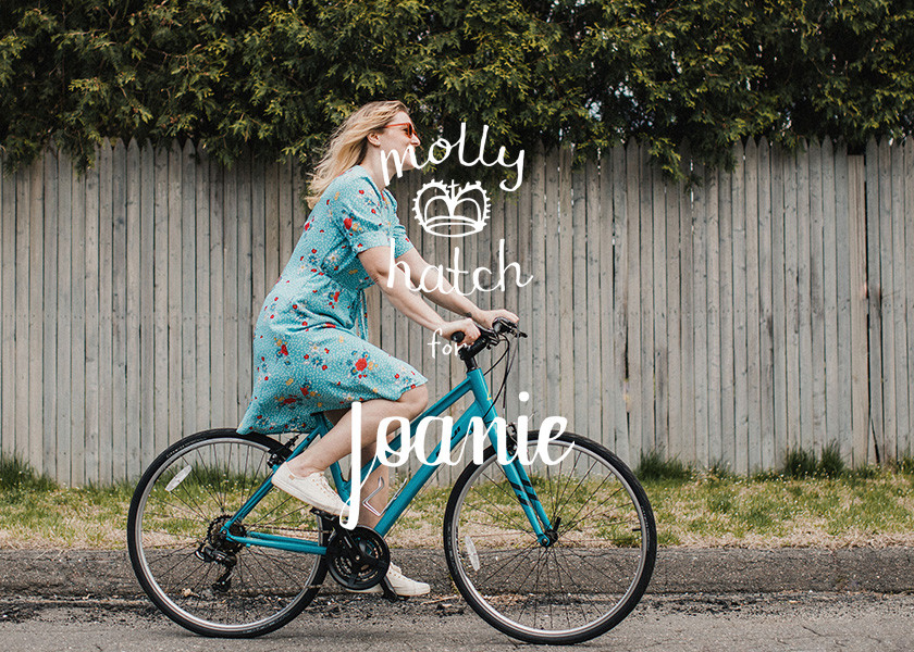 Molly Hatch wearing Judith Dress riding a bicycle