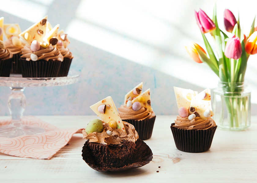 Three frosted chocolate cupcakes with Easter toppings